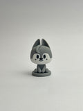 Gray cartoon-like figurine with a white face on a plain background
